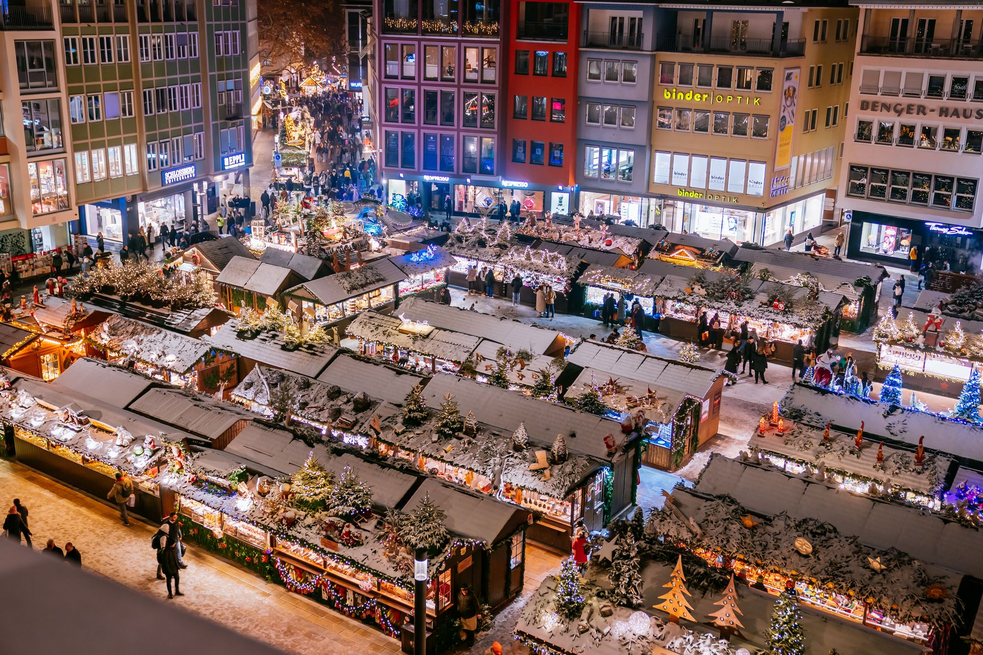 Beleuchtete und verschneite Buden auf dem Stuttgarter Weihnachtsmarkt, von oben gesehen