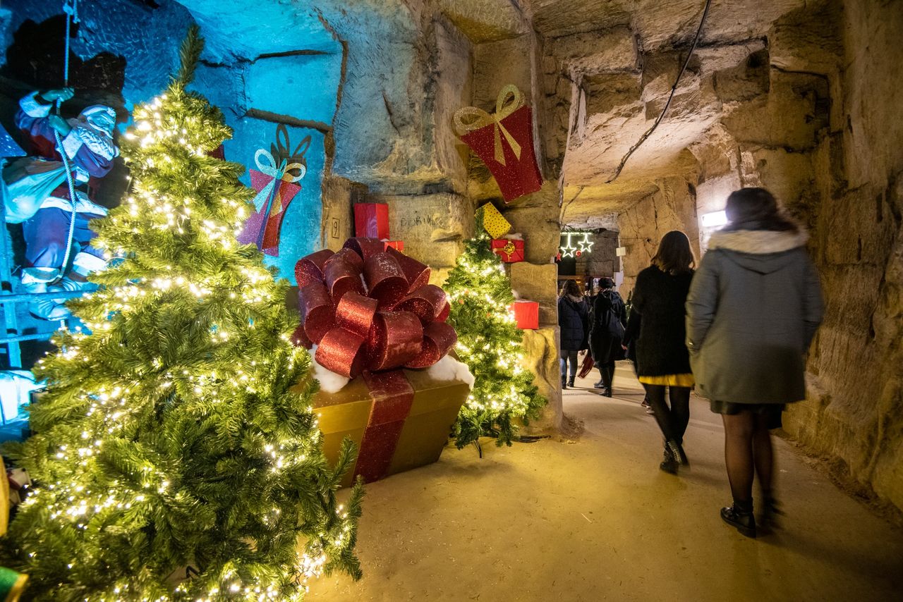 Beleuchtete Weihnachtsbäume und Besucher in der Fluweelengrot in Valkenburg